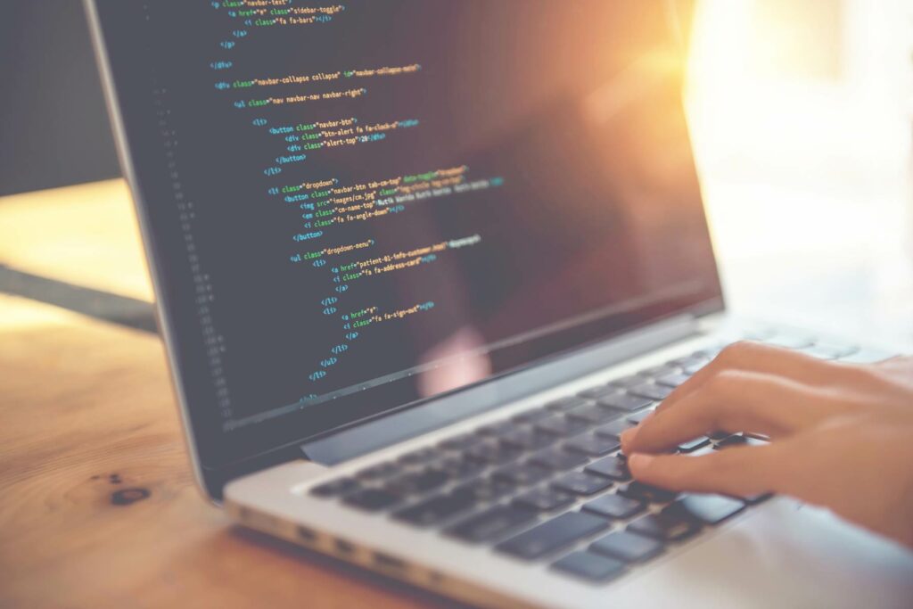 Ein Notebook mit Code auf dem Bildschirm und eine Hand auf der Tastatur